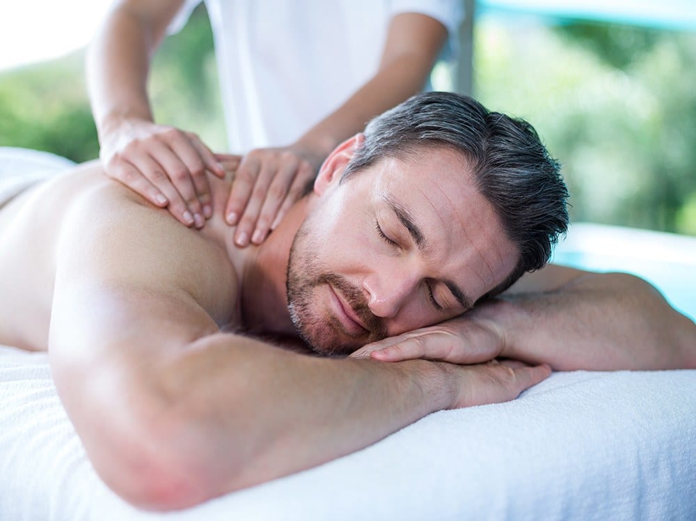 A massage therapist working on a patient's shoulders and upper back